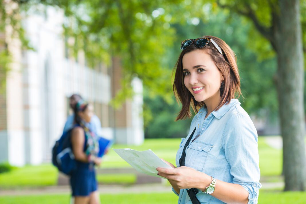 Happy college student using campus man while walking to class