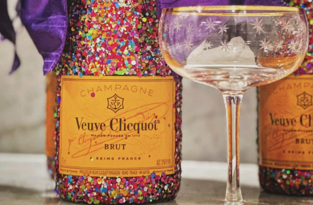 Glitter Veuve Clicquot Bottles from Turning Tables Glitter Veuve Clicquot Bottles from Turning Tables next to a gold rimmed coupe glass